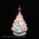 Little white ceramic Christmas tree with colorful round globe lights and a gold snowflake star