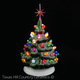Small festive green tree with color lights and red snowflake star