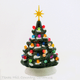 Small 6 inch tall ceramic Christmas tree with colorful lights snow tip branches topped with a gold snowflake style star.